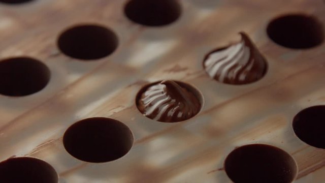 closeup of pastry bag filling candy mold form with chocolate cream Side view close up