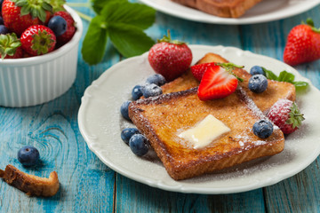 Traditional, delicious, sweet French toast with fruit and butter.