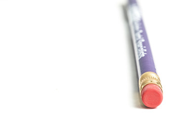 New purple pencil seen from the side of the eraser on white background