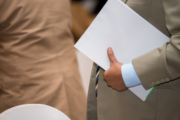 Businessman holding white paper in hand during walk in meeting room.