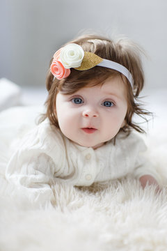 Close-up of a six, seven months old baby girl with blue eyes. Newborn child, little adorable smiling and attentive girl looking surprised at the camera. Family, childhood concept. Christmas Eve