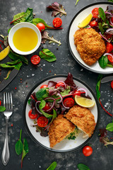 Breaded Chicken Kiev breast stuffed with butter, garlic and herbs served with vegetables in a plate.