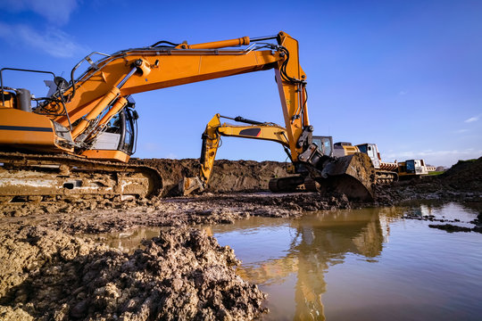 Stillstand von Bauarbeiten wegen N&auml;sse, Bagger spiegeln sich auf Wasserfl&auml;che