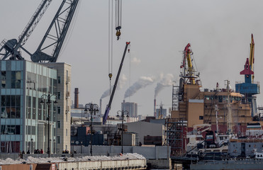 View of the seaport of Vladivostok. Technical facilities and ships in foreground. Large chimneys with smoke in background. Ecology and pollution. Bad air in city. Quality of life. Russia, Vladivostok