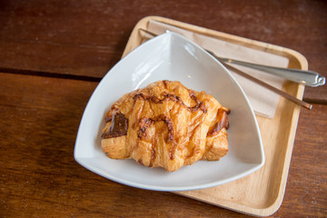 Croissant ham cheese on the white dish and wood plate with wood background.