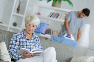 Fototapeta premium woman sitting on sofa with book while male carer standing