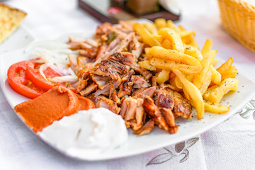 Greek gyros on a plate with French fries and vegetables