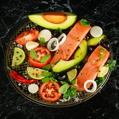 Fillet of red fish and spices on black background.