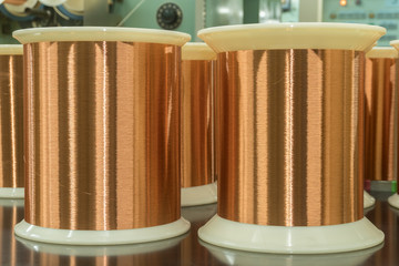 Standard copper wire enamel in a bobbin on the table, steel floor in the factory. The backdrop is a machine. Winding machine