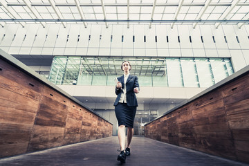 Obraz premium タブレットPCを手に歩く女性（ビジネスイメージ）