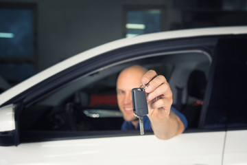 Young car service technician give key of car to customer.