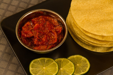 Poppadums stacked, with lime pickle and sliced lime.