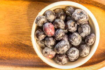 Fresh blueberries in a white ceramic bowl on a bamboo tray