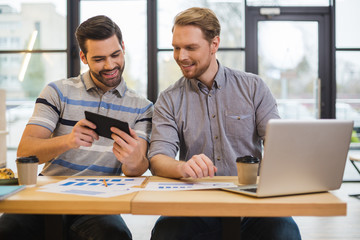 Delighted nice man holding a tablet