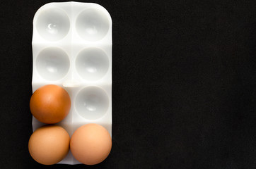 Three chicken eggs white stand on black background.