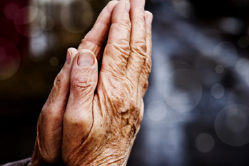 Hands of the old grandmother in prayer on a light background