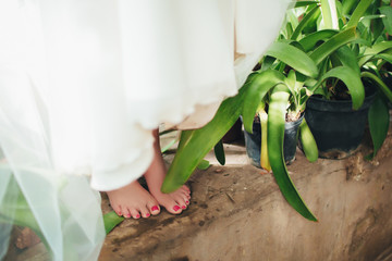 The bride is barefoot with bare feet standing on a step near the water.