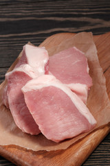 Fresh raw pork steaks on a cutting board  on paper. Close-up