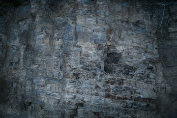 Grunge mystical gray-blue layered rock wall with uneven surface.