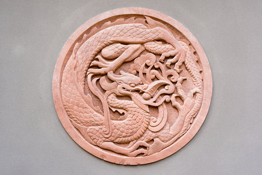 Red circular dragon bas-relief on a grey wall, China