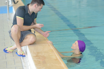 swimming coach holding stopwatch poolside at the leisure center