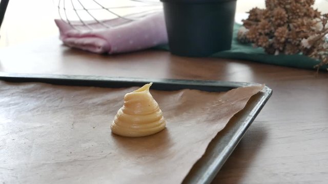 Bakery pastry chef Piping dough for cream puff or profiterole or choux creme on baking tray.
