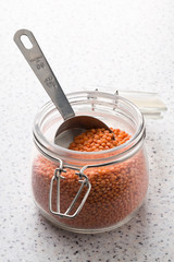 Raw red, dried  lentils in measurement scoop and glass