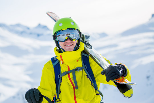Photo of sporty man wearing helmet with ski on his shoulder