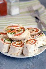 Rolls of thin pancakes with smoked salmon, cream cheese, chives and lettuce.