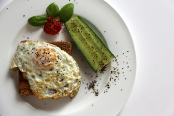 Sandwich mit Spiegelei und Gurke auf weißem Teller