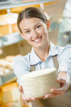 Woman holding a wheel of cheese