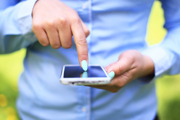Woman using mobile smart phone in the park.