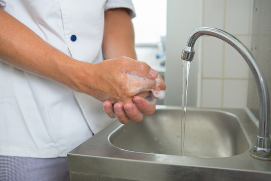 man washing hands in kitchen