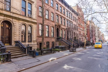 Fotobehang Schilderachtige, met bomen omzoomde straat van historische brownstone-gebouwen in de wijk West Village van Manhattan in New York City, NYC, VS. Traditionele gele taxi auto rijden langs straat. © kasto
