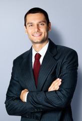 Happy businessman with crossed arms, on grey