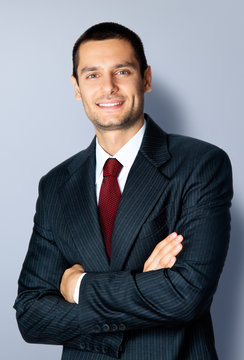 Happy businessman with crossed arms, on grey