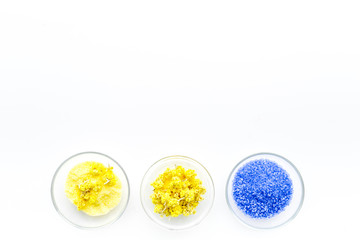 Colorful spa salt. Yellow spa salt with delicate spring flowers and violet lavender spa salt on white background top view copy space
