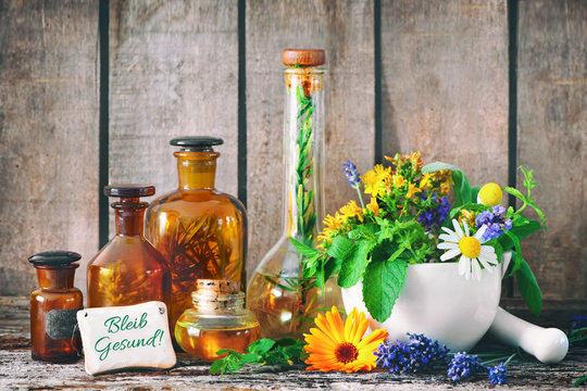 Kr&auml;utertee mit Medizinflaschen und heilenden Kr&auml;utern im M&ouml;rser. Bleib gesund