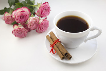 A cup of coffee cinnamon and roses on a white background