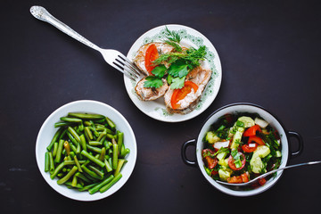 selection of healthy food. String beans, tomato and cucumber salad, baked fish in plates.