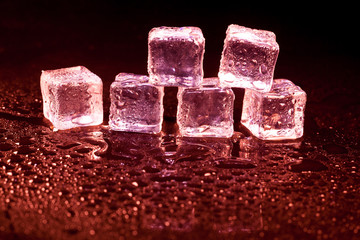 Red ice cubes on black background.