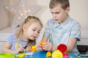Kids playing and having fun with clay, plastiline at home or kindergarten