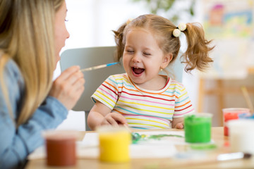 mom and kid daughter painting together at home
