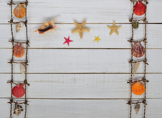 colorful seashells on a decorative  fishing net and starfish on white retro wooden background. Marine life decoration background. summer vacation. space for text