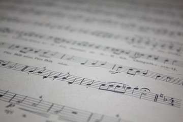 Old music sheet. Defocused blurry musical symbols detail photo.