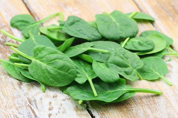 Stack of fresh baby spinach leaves on rustic wooden surface
