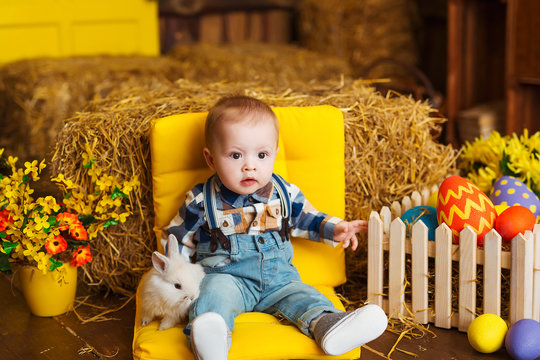Little boy playing with white rabbit and carrot indoor. Spring easter fun for children. Happy childhood concept.