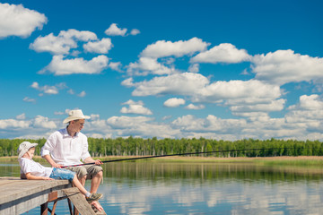 Fototapeta premium relaxed boy with his father on a fishing trip on a beautiful lake