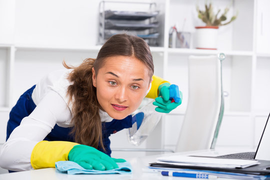 Smiling female in  cleaning surfaces at office