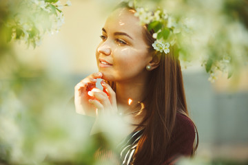 young woman with dreamy stands in the midst of a blossoming tree.